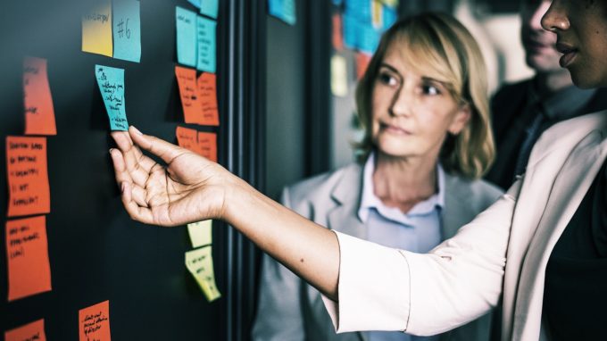 Business women looking at sticky note on a discussion board