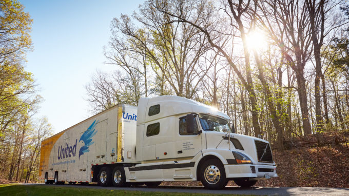 Hilldrup truck on the road with the sun peaking through the trees