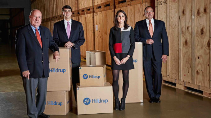 Charles G., Charlie, Jordan, and Charles W. McDaniel posing in a storage warehouse surrounded by moving boxes