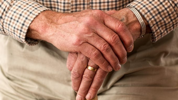 Elderly man's hands holding a cane.