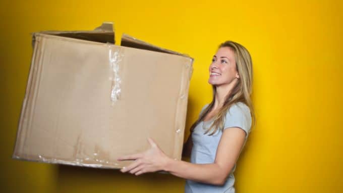 Young woman holding a moving box.|Young woman holding moving box.