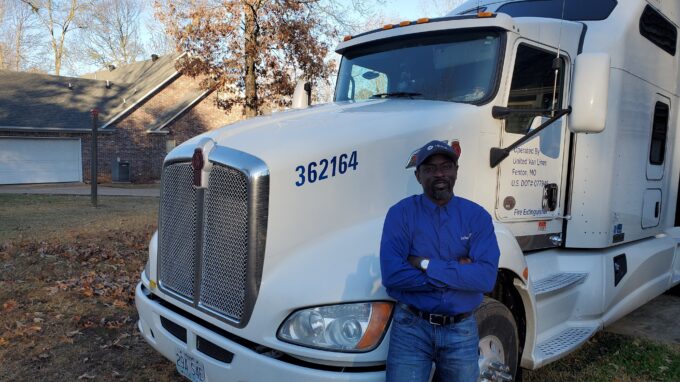 Olu, Stafford Van Operator, stands by his truck.