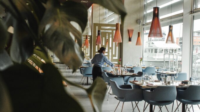 Picture of a restaurant with empty tables and a waitress.