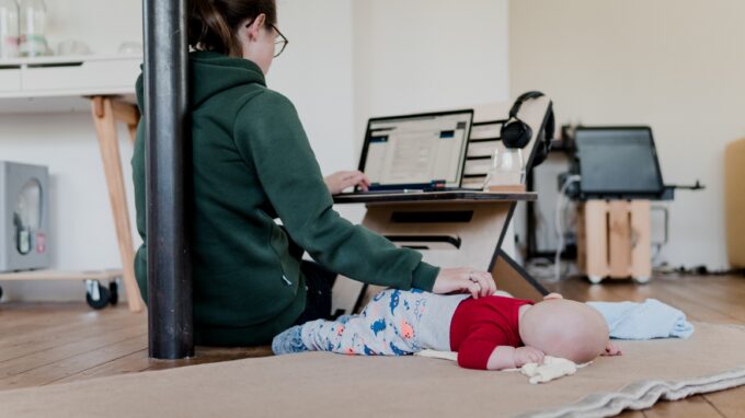 Woman working from home and taking care of her infant.