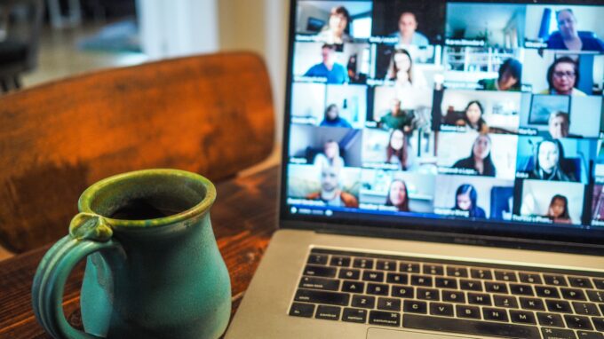 Picture of a desk with a coffee mug and a laptop with a Zoom screen up.