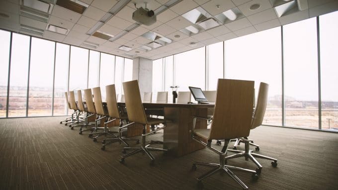 Conference room with a large table and chairs against a wall of windows.