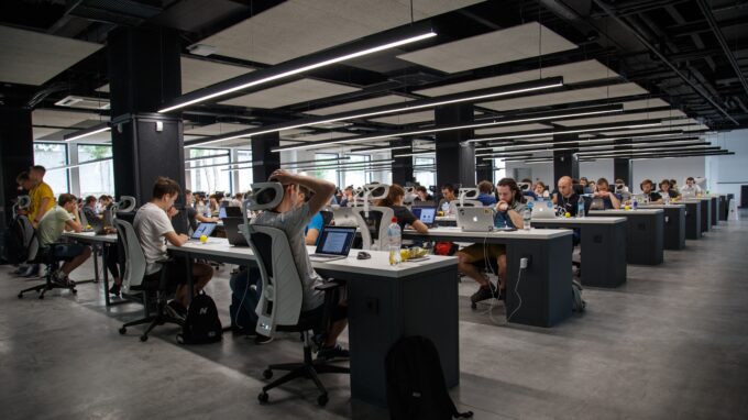 Open office with rows of tables, computers and employees.