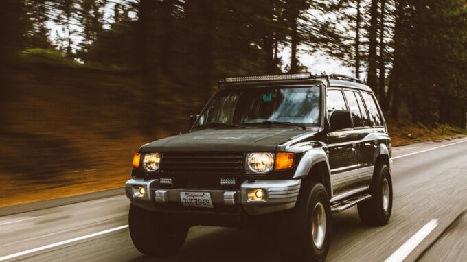 Green SUV on highway in forest