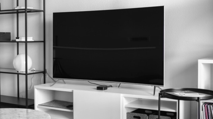 Large TV on a wall above a white entertainment console.