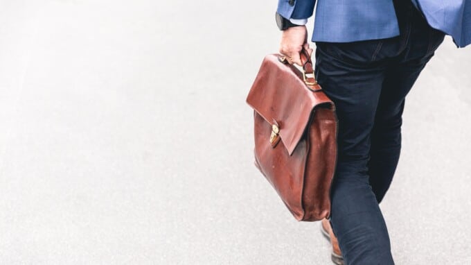 Man in a blue suit carrying a leather briefcase