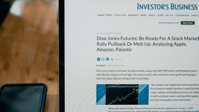 An open laptop on a desk with an investment news website pulled up.