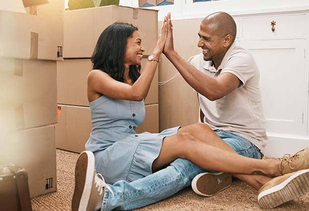 Couple giving each other a high five after moving into their new home.