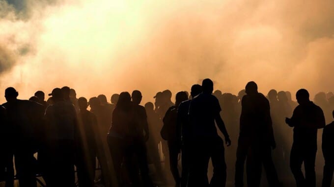 Silhouette of people in a crowd with smoke