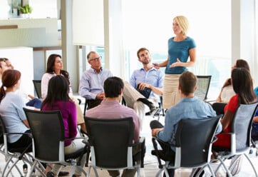 Female HR representative speaking to a team of employees who are seated around her in a circle