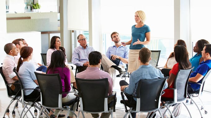 Female HR representative speaking to a team of employees who are seated around her in a circle