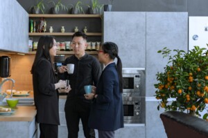 coworkers in office kitchen with reusable mugs