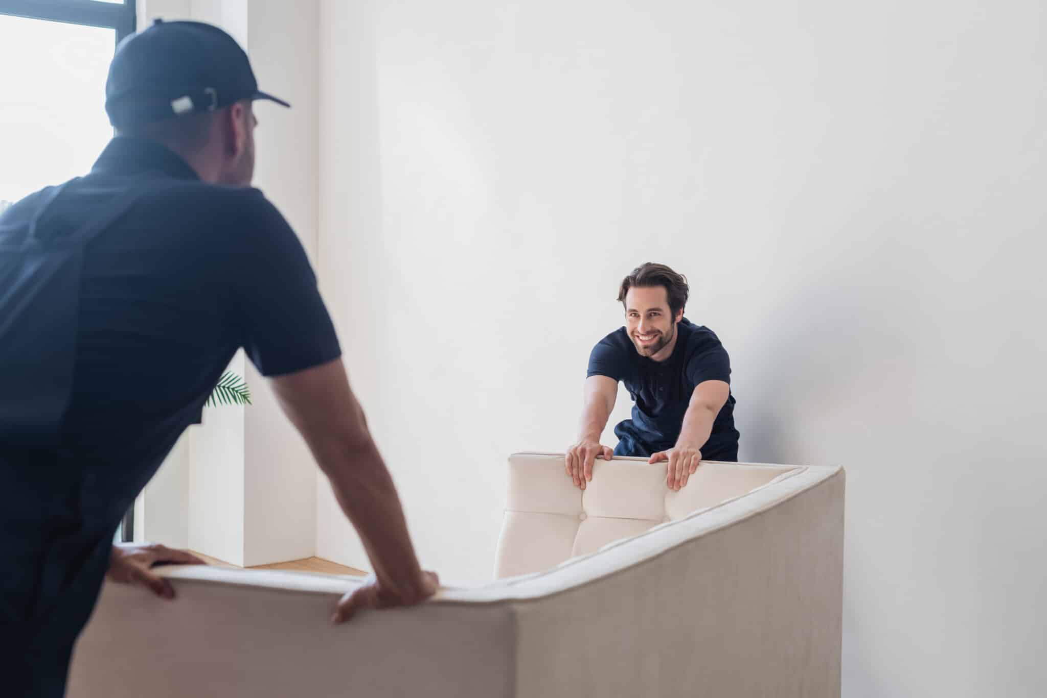 Delivery team placing unpacked Sofa in customers home.