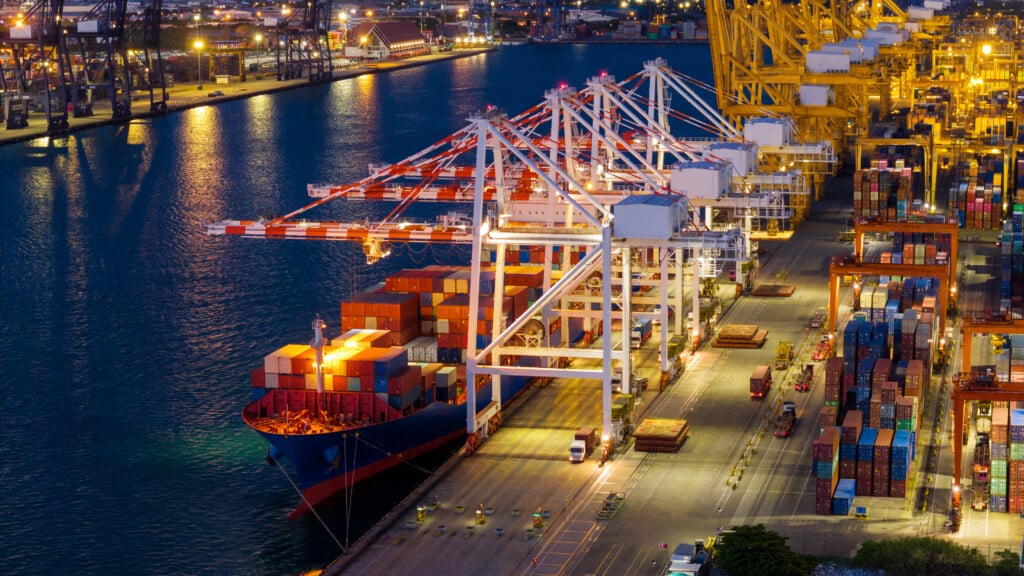 crane loading cargo container from truck to container ship in the international terminal logistic sea port concept freight shipping by ship. industry transportaion
