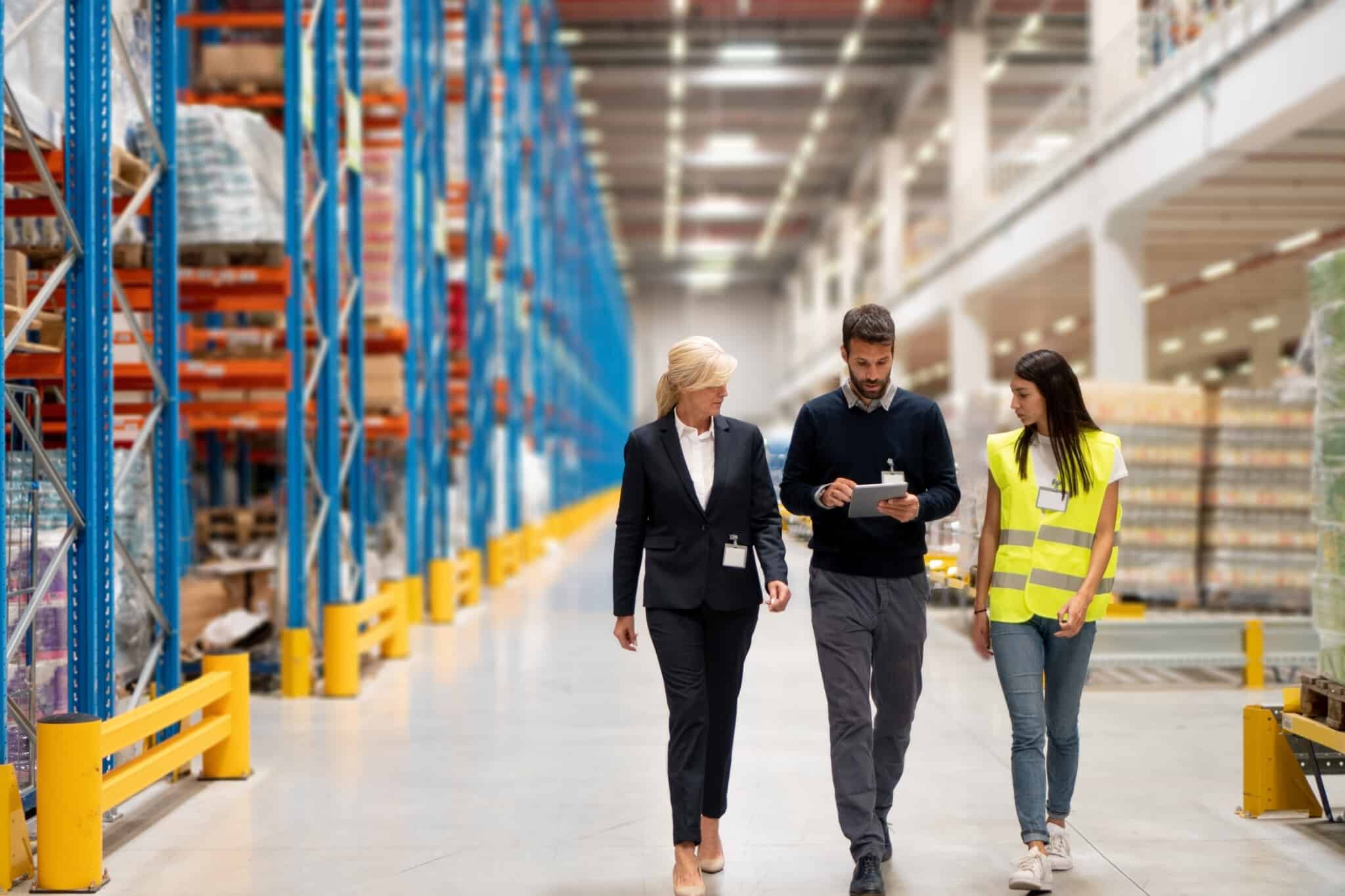 two business people and a moving associate walking through a warehouse